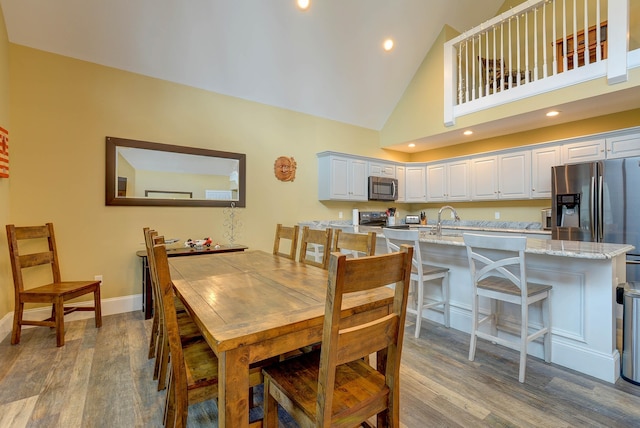 dining area featuring wood finished floors, high vaulted ceiling, baseboards, and recessed lighting