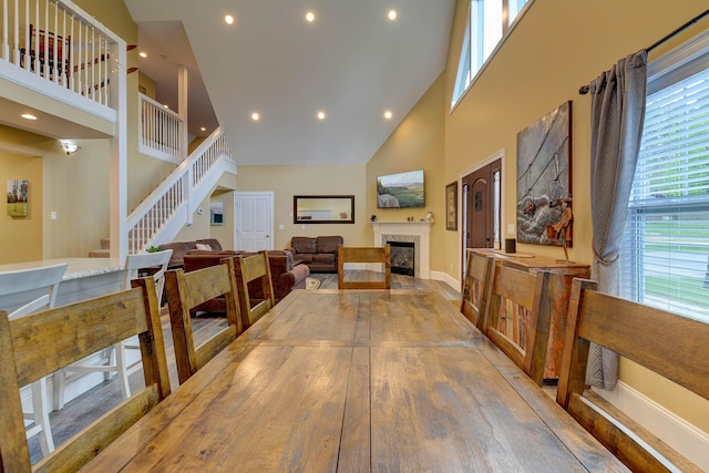 dining area with a high ceiling, a fireplace, recessed lighting, stairway, and baseboards