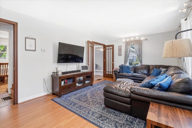 living area with wood finished floors, baseboards, and french doors
