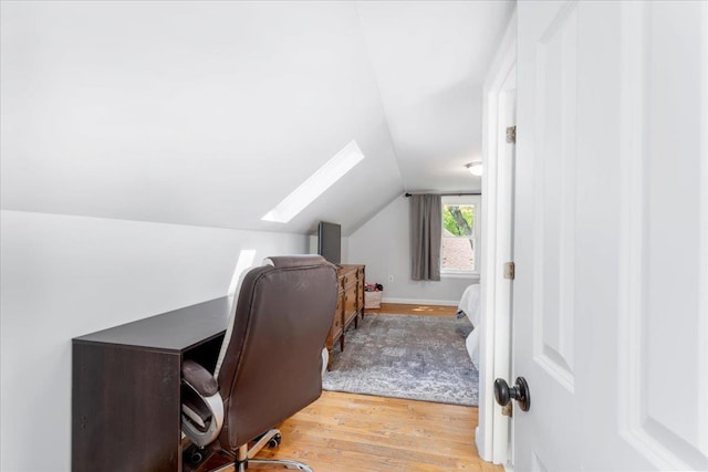 home office featuring wood finished floors, vaulted ceiling, and a skylight