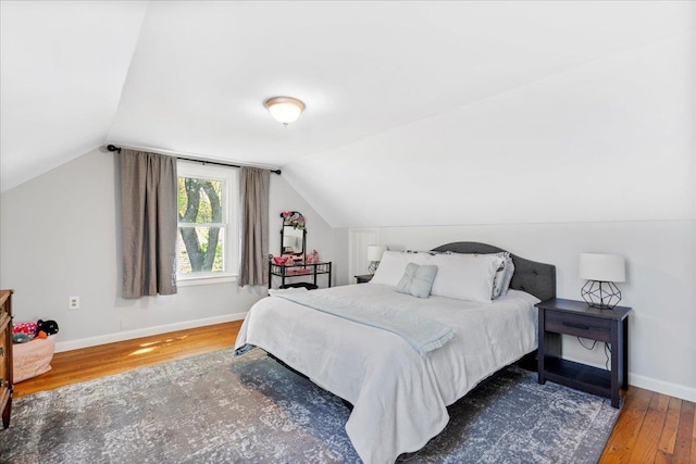bedroom with wood finished floors, baseboards, and lofted ceiling