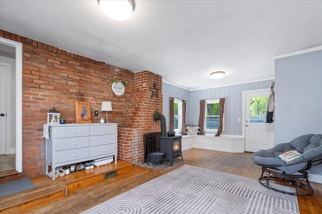 bedroom with a wood stove, wood-type flooring, and crown molding