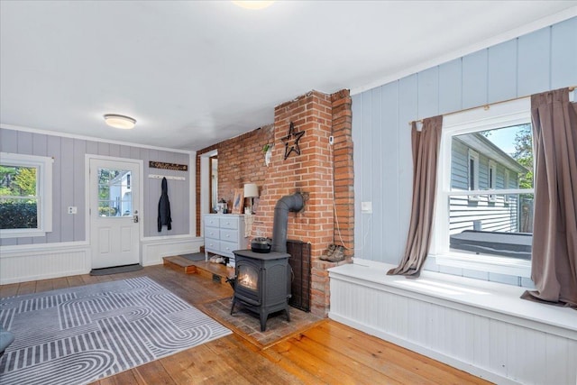 foyer entrance featuring a wood stove and wood finished floors