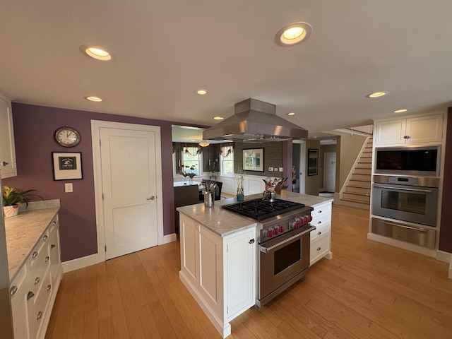 28-28A Ridge Rd, Hollis, NH 03049 - kitchen with appliances with stainless steel finishes, island exhaust hood, a warming drawer, white cabinets, and light wood-style flooring