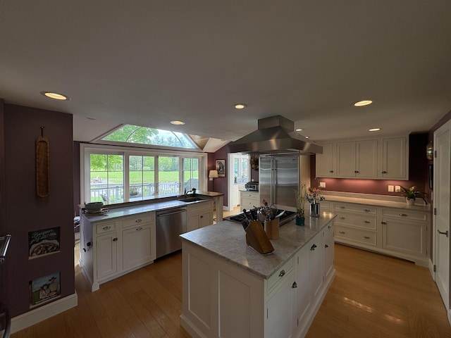 28-28A Ridge Rd, Hollis, NH 03049 - kitchen featuring island range hood, stainless steel appliances, light wood finished floors, white cabinetry, and a sink