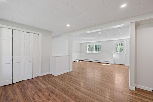 41 Elk Dr, Bedford, NH 03110 - below grade area featuring a baseboard heating unit, wood finished floors, a drop ceiling, baseboards, and recessed lighting