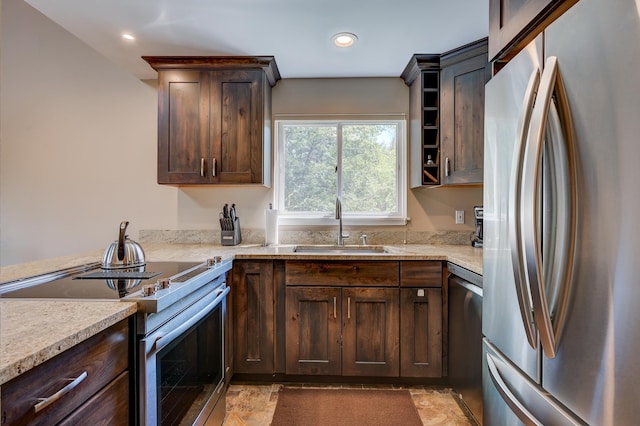 kitchen with appliances with stainless steel finishes, a sink, dark brown cabinetry, light countertops, and recessed lighting