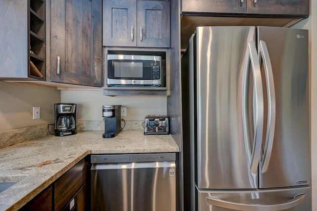 kitchen featuring appliances with stainless steel finishes, dark brown cabinetry, and light stone countertops