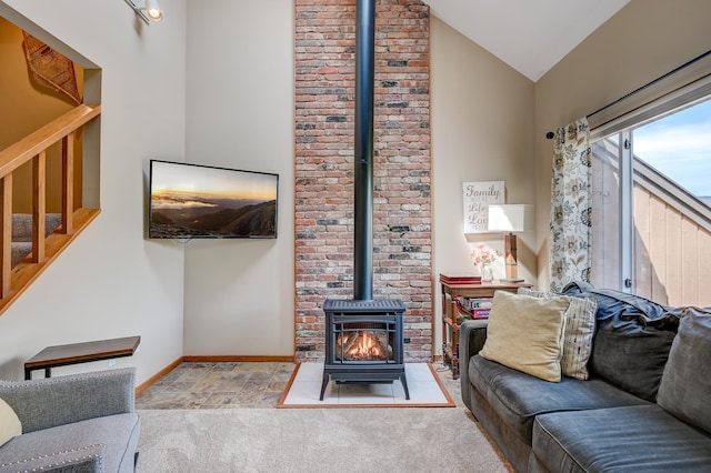 living room featuring stairway, a wood stove, lofted ceiling, baseboards, and carpet