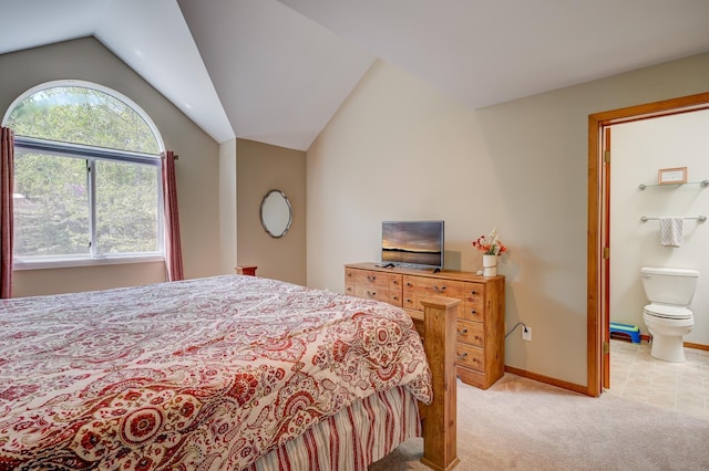 bedroom with light colored carpet, vaulted ceiling, baseboards, and connected bathroom