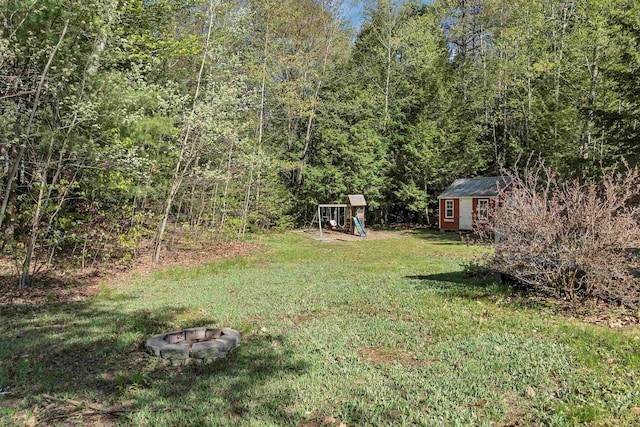268 Lesmerises Rd, Loudon, NH 03307 - view of grassy yard with a playground, a storage shed, an outbuilding, and a forest view