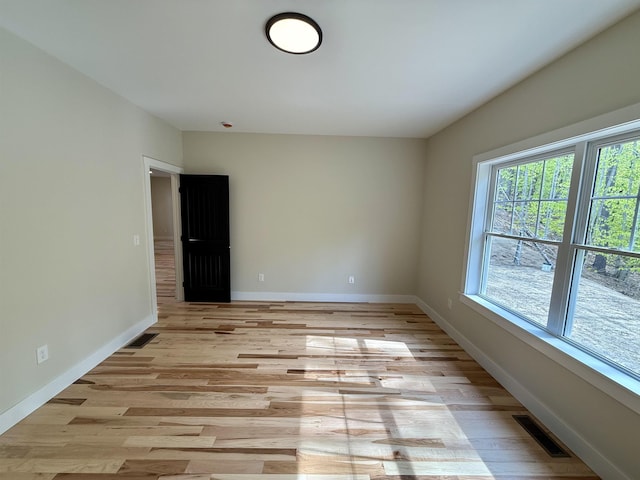 spare room featuring light wood-type flooring and baseboards