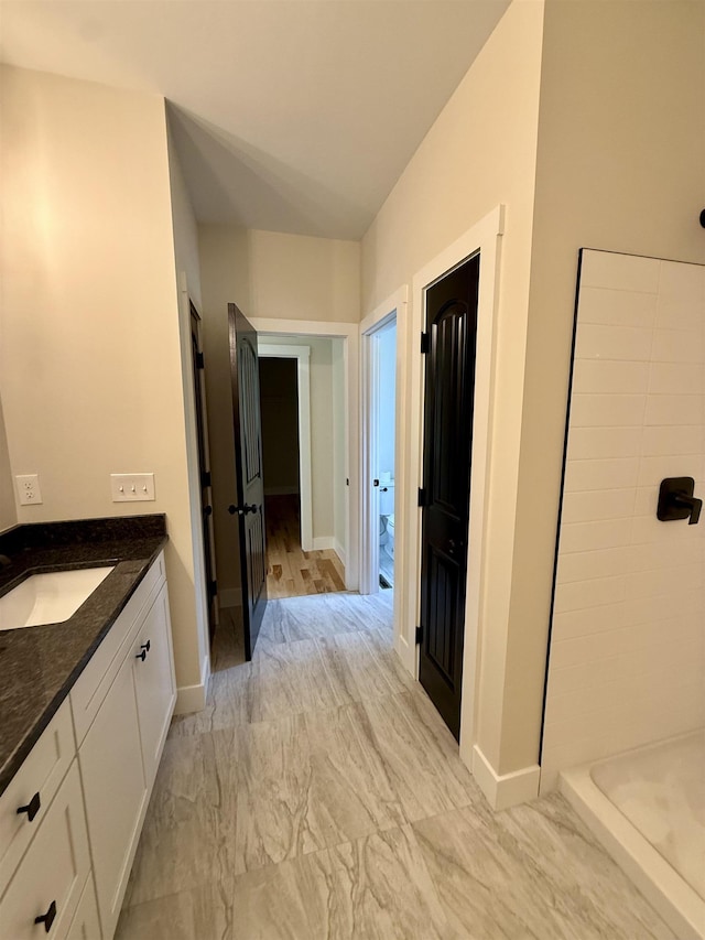 full bathroom with baseboards, vanity, a shower, and marble finish flooring