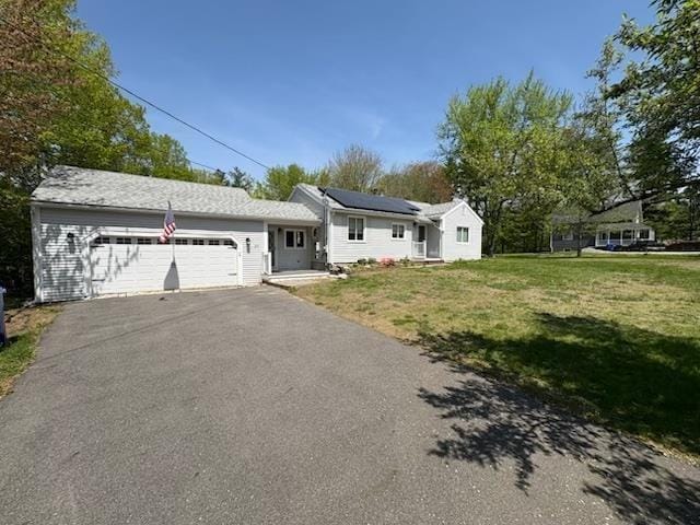 view of front facade with an attached garage, a front lawn, asphalt driveway, and roof mounted solar panels