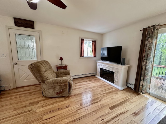 living room with a baseboard radiator, healthy amount of natural light, and light wood-style flooring