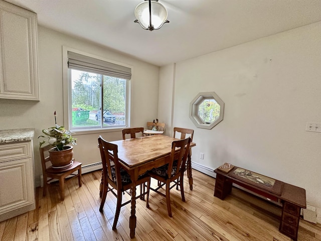 dining space with light wood finished floors and a baseboard radiator