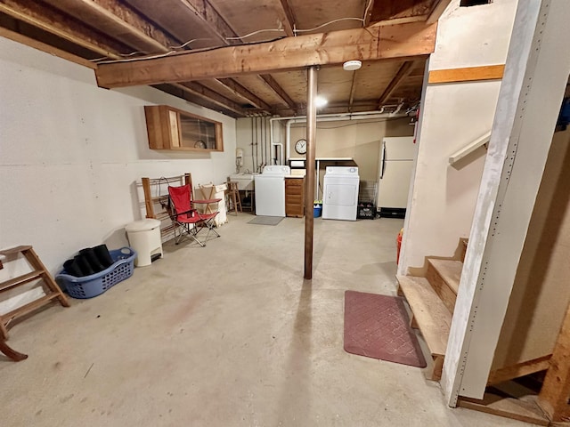 unfinished basement featuring freestanding refrigerator and washer and clothes dryer