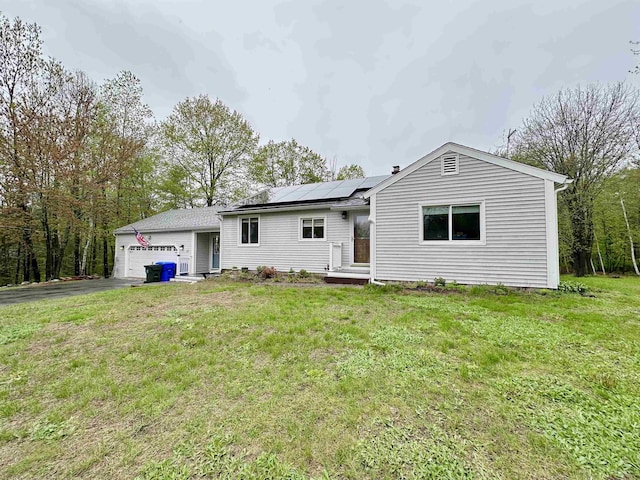 view of front of house with a garage, roof mounted solar panels, asphalt driveway, and a front yard