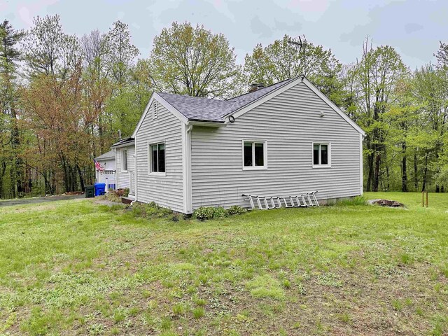 view of side of home with a lawn and a shingled roof