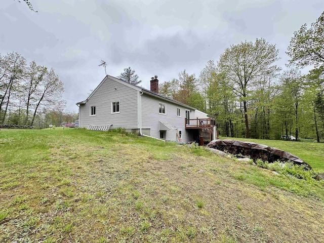 back of house featuring a chimney, a deck, and a yard