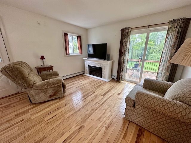 living area featuring a baseboard radiator, light wood finished floors, and a tiled fireplace