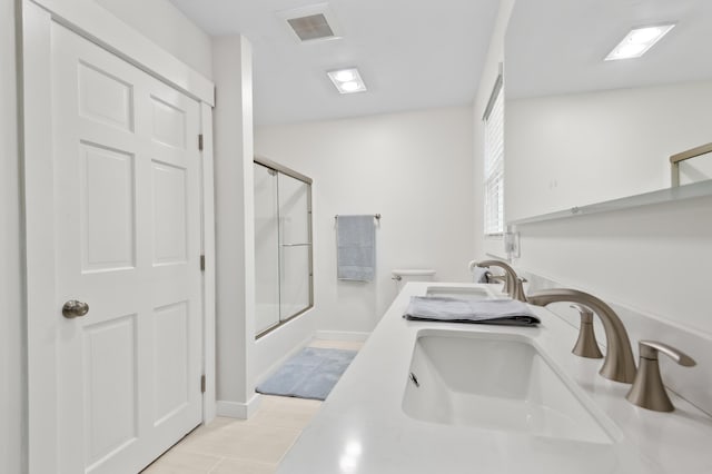 full bath featuring bath / shower combo with glass door, double vanity, and tile patterned flooring