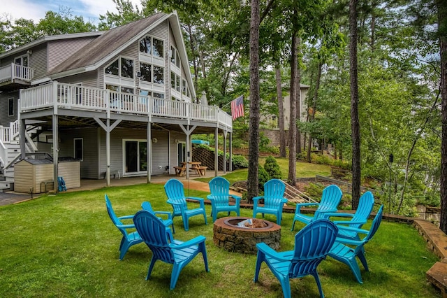 back of house featuring an outdoor fire pit, a wooden deck, stairs, a lawn, and a patio area