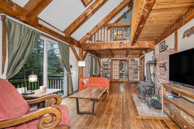 living area with beamed ceiling, hardwood / wood-style floors, a wood stove, and french doors