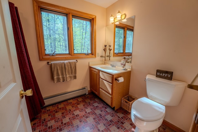 half bathroom featuring a baseboard heating unit, toilet, vanity, and brick patterned flooring