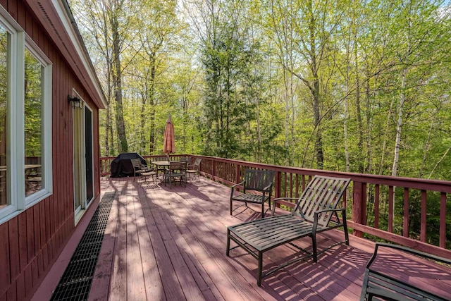 wooden deck with outdoor dining space and a wooded view