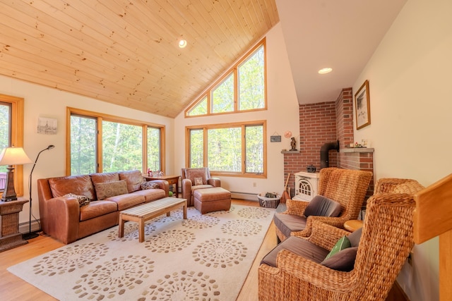 living area featuring a wood stove, a baseboard heating unit, wood finished floors, plenty of natural light, and high vaulted ceiling