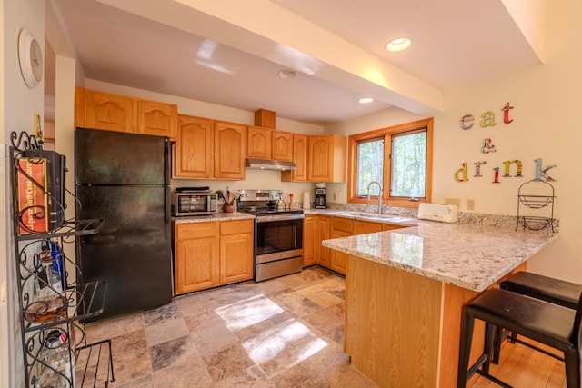kitchen featuring stainless steel range with electric cooktop, freestanding refrigerator, a sink, a peninsula, and under cabinet range hood