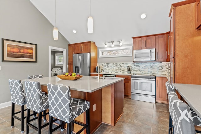1385 Front St, Manchester, NH 03102 - kitchen with appliances with stainless steel finishes, a sink, washing machine and clothes dryer, tasteful backsplash, and light countertops