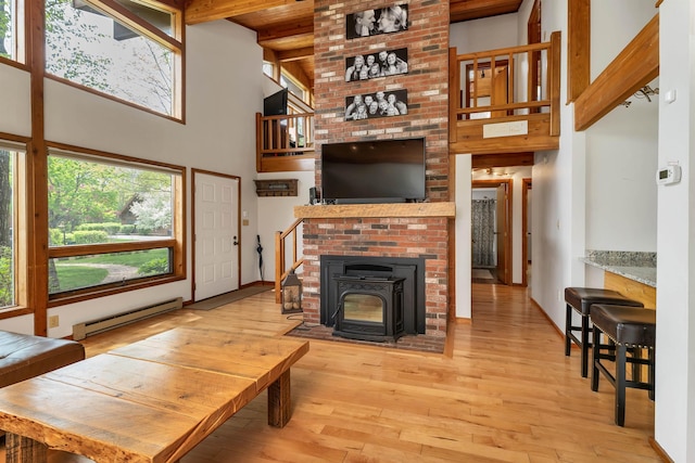 living room featuring baseboard heating, hardwood / wood-style flooring, a high ceiling, beamed ceiling, and wood ceiling
