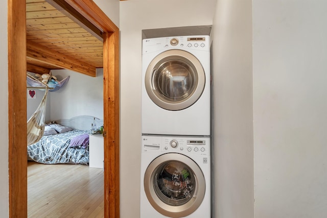 washroom featuring stacked washer / drying machine, wood ceiling, and wood finished floors