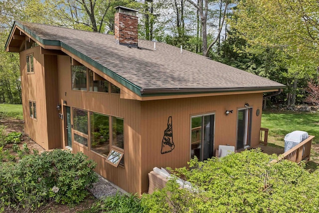 view of home's exterior with a chimney and a shingled roof