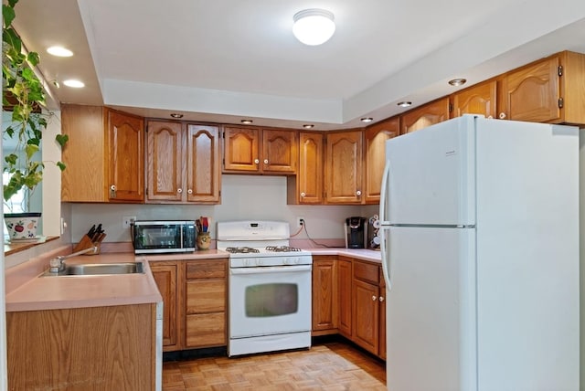 kitchen featuring white appliances, recessed lighting, a sink, light countertops, and brown cabinetry