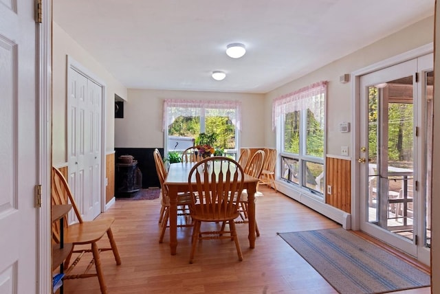 dining space with a baseboard radiator, a wainscoted wall, and light wood finished floors