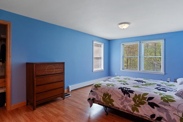 bedroom featuring baseboards, wood finished floors, and a baseboard radiator