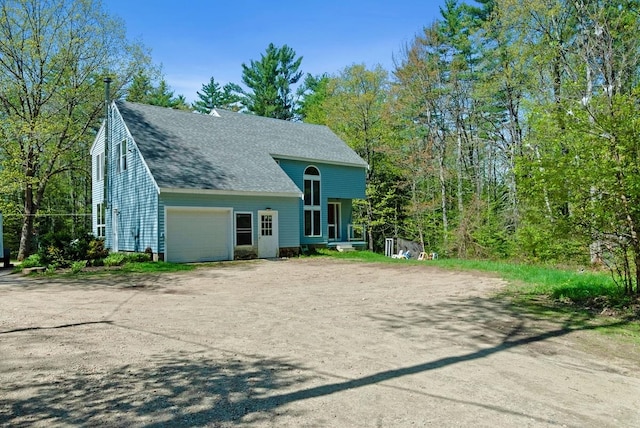 view of front of house with driveway, an attached garage, and a shingled roof