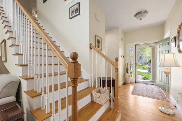 foyer featuring wood finished floors, stairway, and baseboards