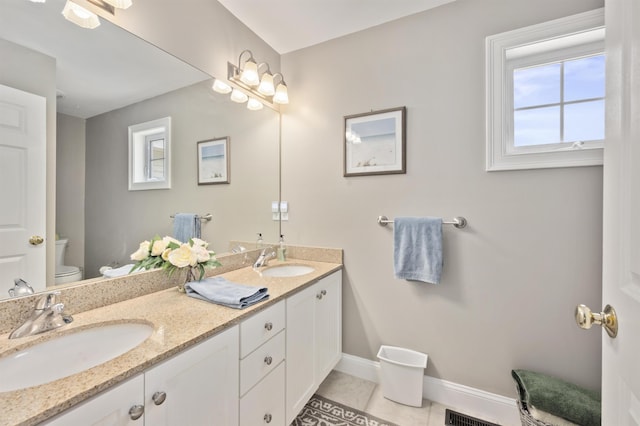 bathroom featuring toilet, tile patterned floors, baseboards, and double vanity