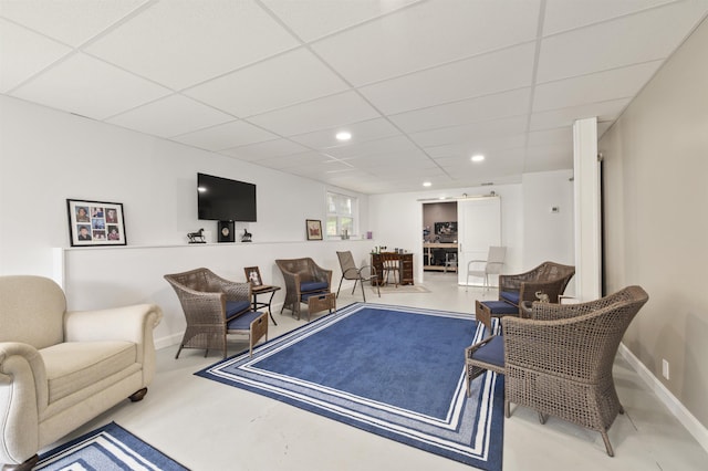 living room featuring a paneled ceiling, baseboards, and recessed lighting