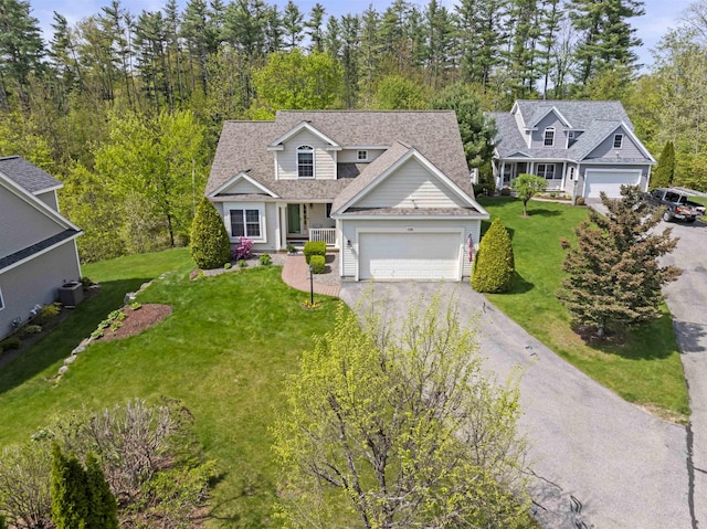 traditional-style home featuring driveway, a front yard, and an attached garage