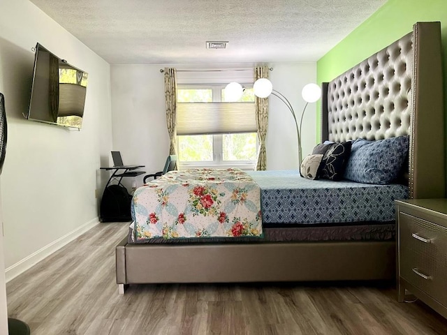 bedroom featuring wood finished floors, a textured ceiling, and baseboards