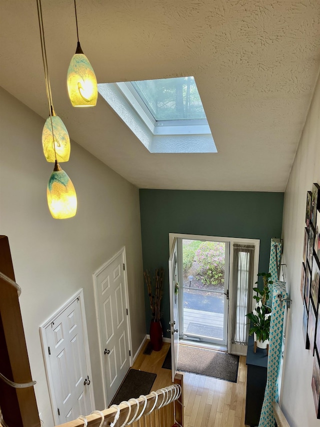 foyer featuring a skylight, wood finished floors, and vaulted ceiling