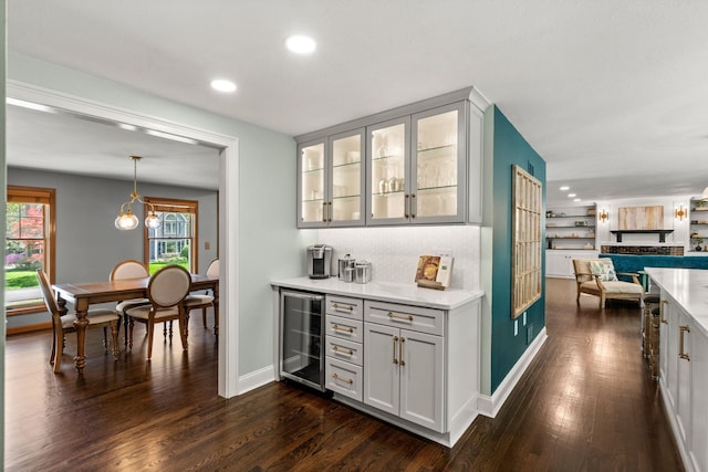 indoor dry bar featuring wine cooler, dark wood-type flooring, recessed lighting, baseboards, and decorative light fixtures