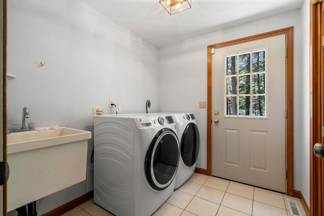 laundry room featuring washing machine and dryer, light tile patterned floors, and baseboards