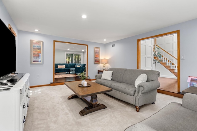 living room featuring recessed lighting, stairs, baseboards, and light colored carpet