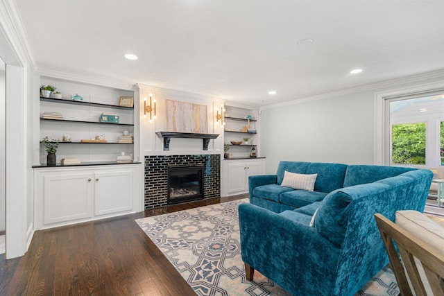living area featuring dark wood-type flooring, ornamental molding, a tiled fireplace, and recessed lighting